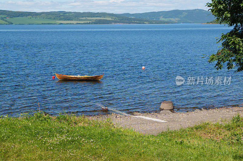 Shore of the Mjøsa near Hamar. In the foreground a wooden rowboat. Mjøsa is the largest lake in Norway. Seen on the pilgrimage path St. Olavsweg from Oslo to Trondheim.